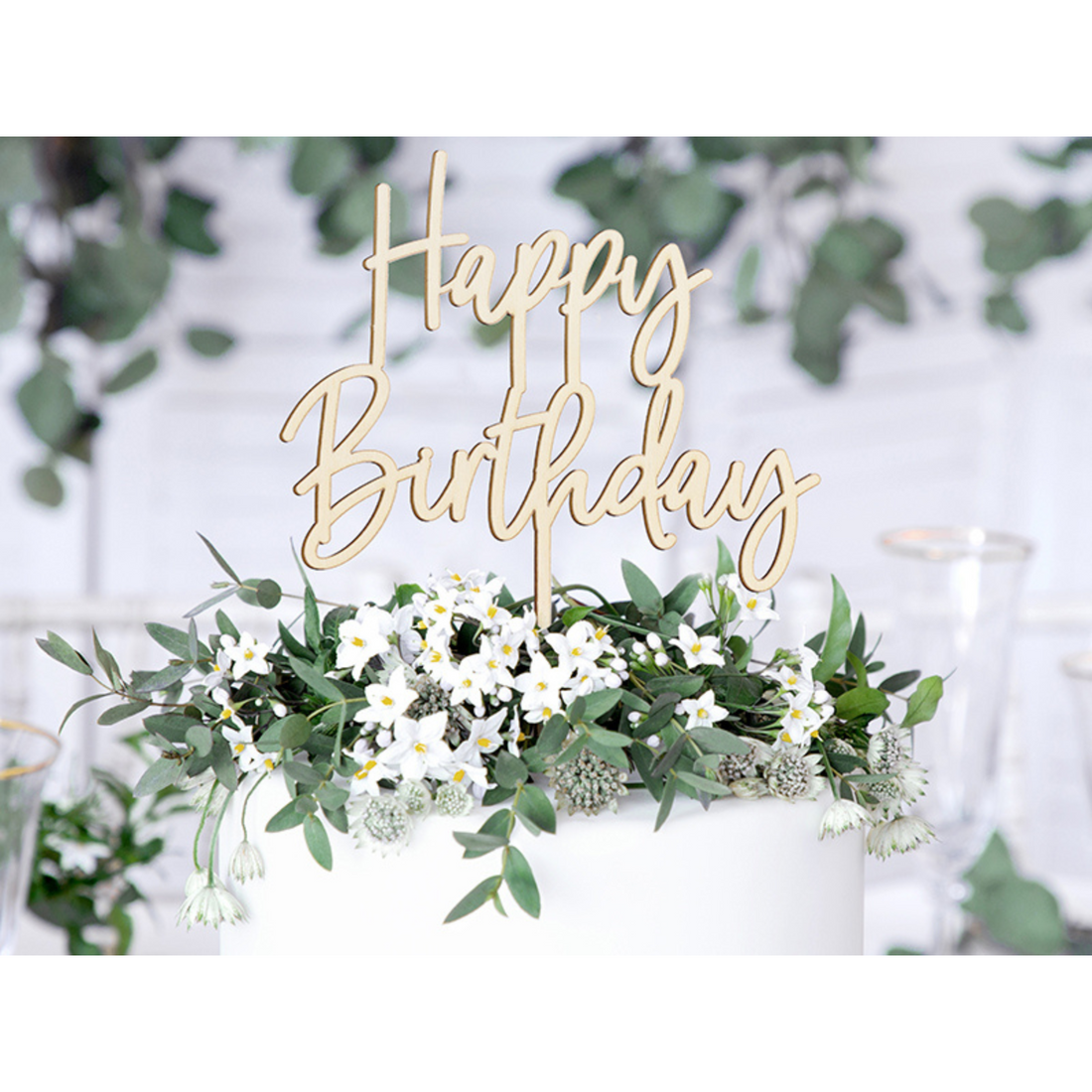Taart met daar bovenop een taarttopper in het hout met als opschrift Happy Birthday 